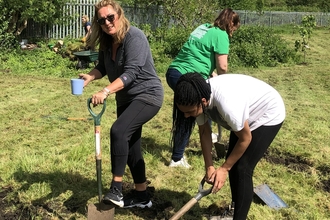 Three women digging in a green field. 