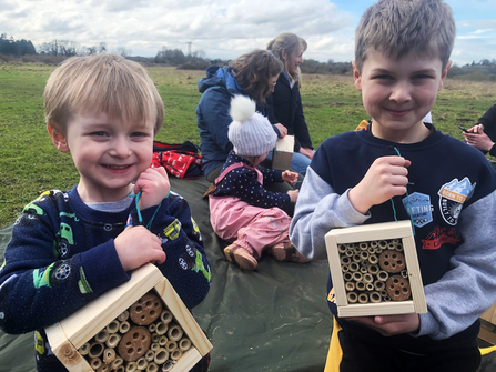 Two boys show their handmade bee hotels