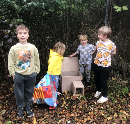 Children stand with handmade hedgehog house