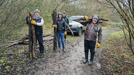 Team members from Clegg carrying large wooden poles