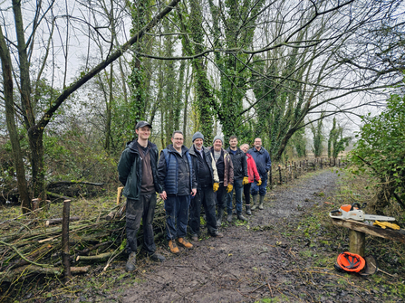 Clegg team members stand in front of dead hedge they built